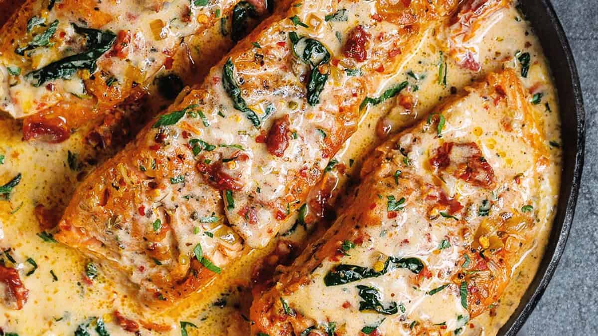 A close up image of Tuscan Salmon in Cream Sauce in a black pan.