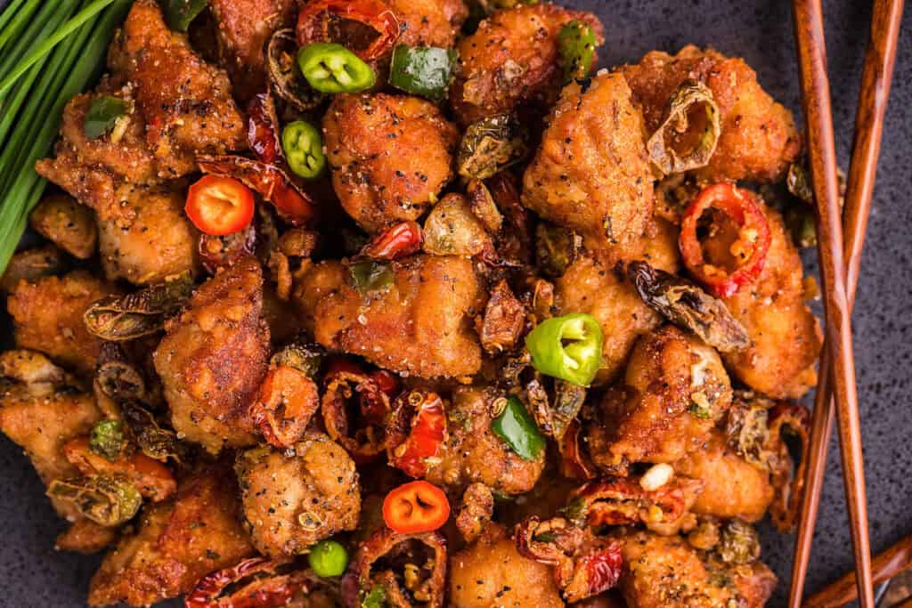 A plate of Salt & Pepper Pork Chop Bites garnished with red pepper and green onions.