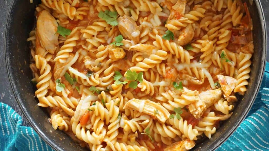 A close up image of Chicken and Pasta with tomato sauce in a pan.