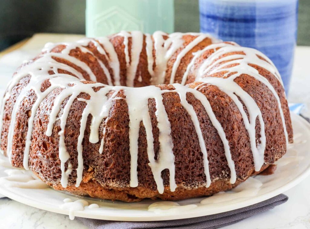 a close up image of a Cinnamon Pecan Breakfast Bundt Cake on a white plate.