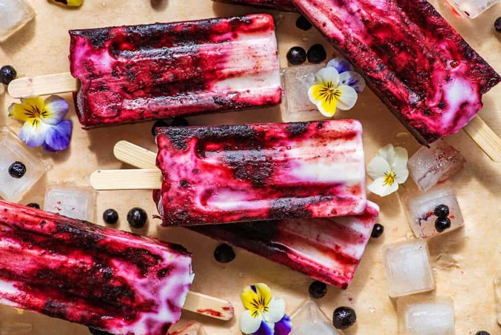 Vibrant Lemon Blueberry Popsicles displayed with flowers.