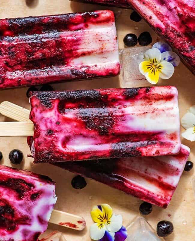 Vibrant Lemon Blueberry Popsicles displayed with flowers.