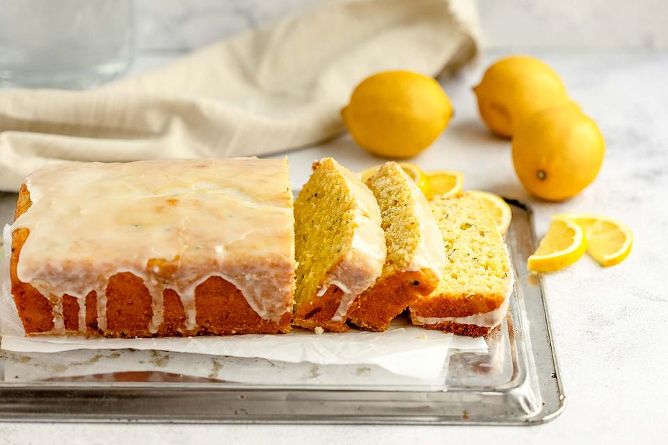 A sliced, iced Lemon Zucchini Loaf on baking paper.