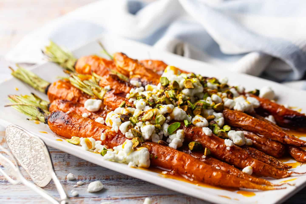 A close up image of Orange Sriracha Glazed Carrots with Goat Cheese and Pistachios