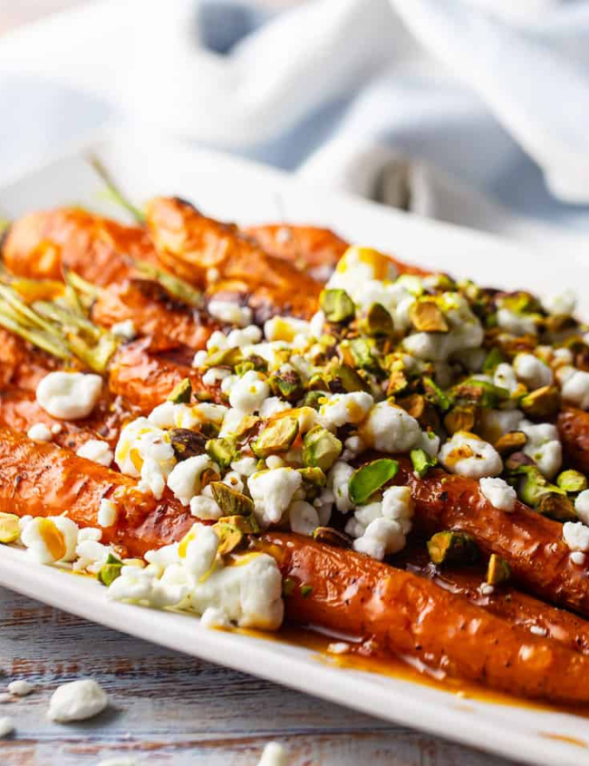 A close up image of Orange Sriracha Glazed Carrots with Goat Cheese and Pistachios