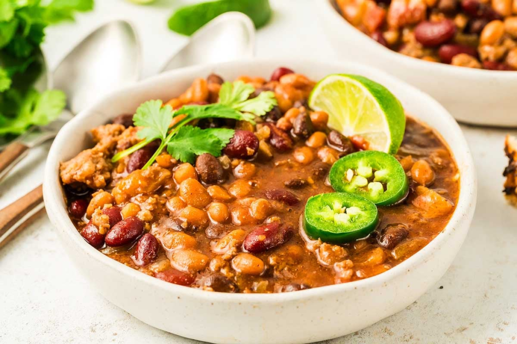 A bowl full of Slow Cooker Cowboy Beans topped with herbs