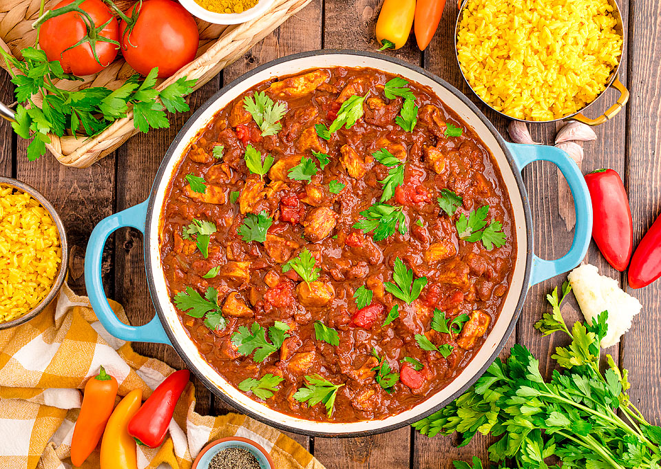 A Chicken Madras Curry in a skillet scattered with herbs.