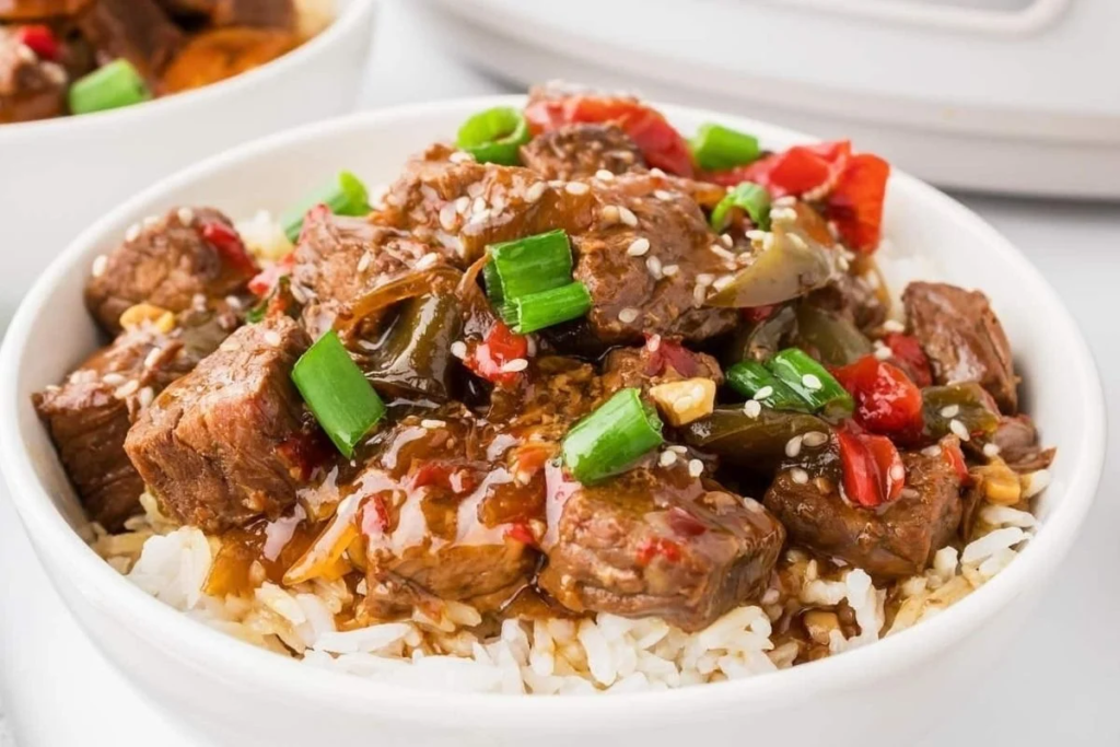 A bowl of Slow Cooker Beef Teriyaki.  topped with green onions.