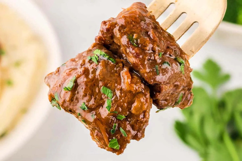 a close up image of Crockpot Steak Bites on a fork.