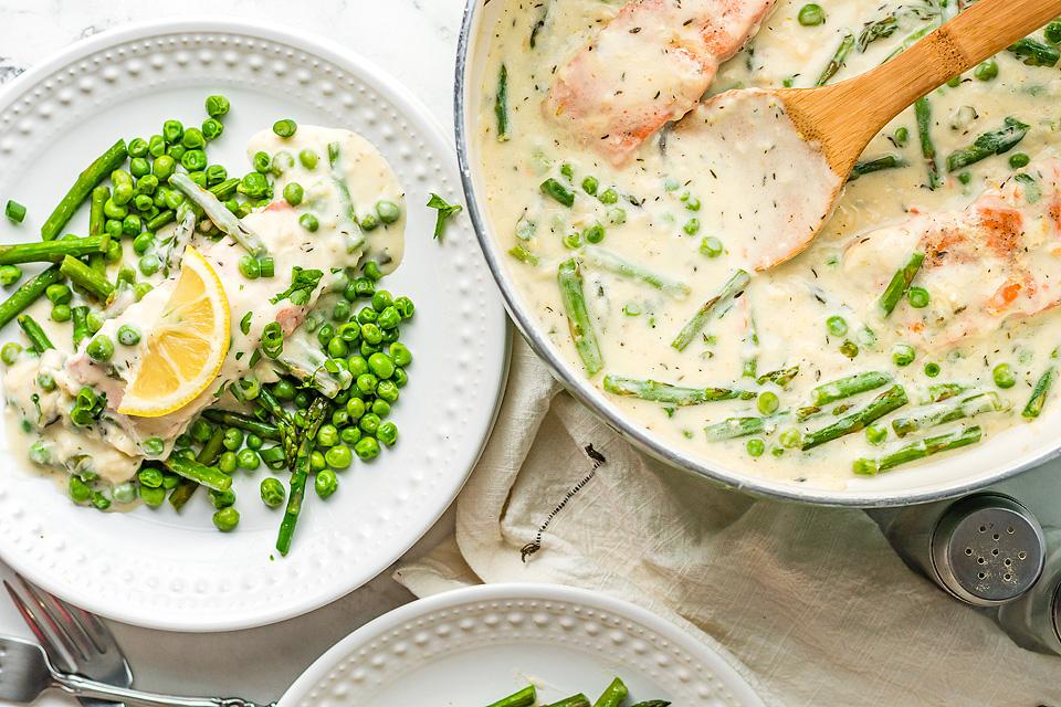 Two plates of Salmon and Fresh Vegetables with a Creamy White Wine Sauce. 