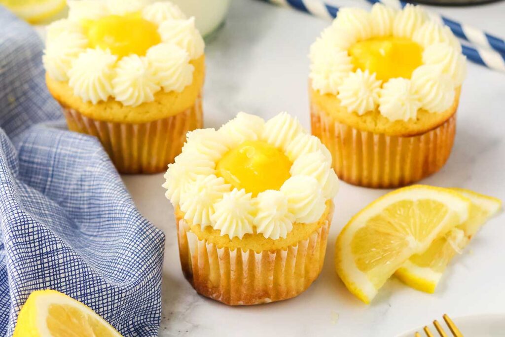 Three Lemon Stuffed Cupcakes with lemon cured and frosting forming a flower on top.