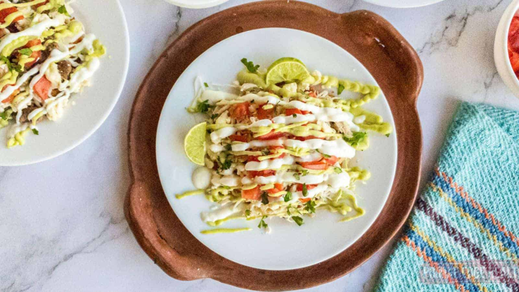 Chicken tostadas with cheese shell on plate on a terra cotta tray.