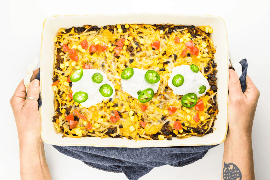 Two hands holding a pan of a Vegan Taco Casserole.