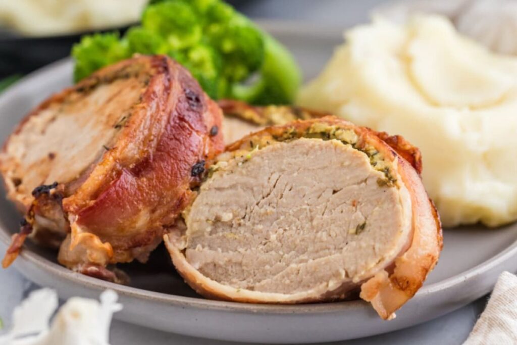 Air Fryer Bacon Wrapped Pork Tenderloin on a plate with mashed potatoes.