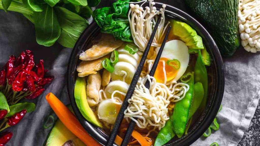 Keto Ramen Chicken Noodles in a black bowl with various vegetables and boiled egg. 