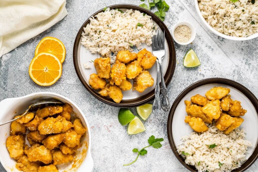 An overhead image of three bowls of Orange Chicken over rice.