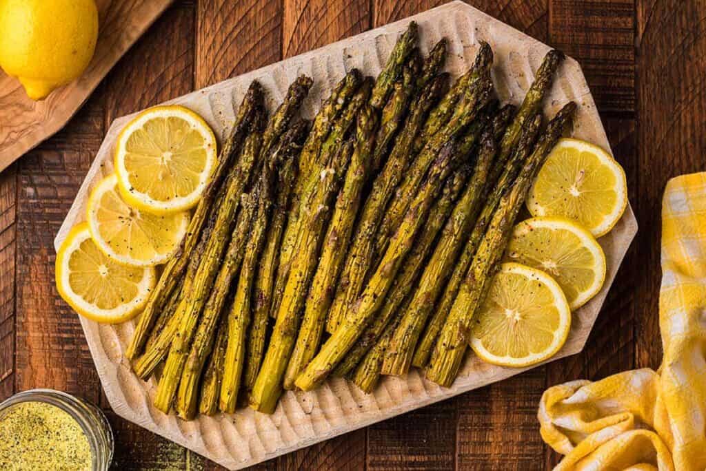 A platter of Smoked Asparagus with lemon slices.