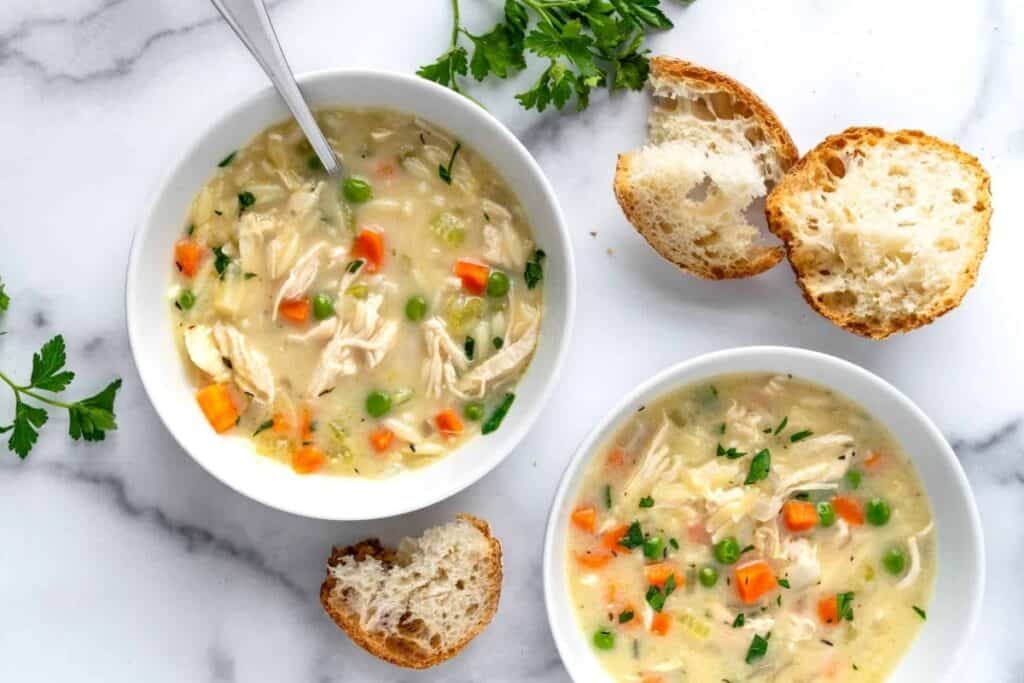 An overhead image of two bowls of Creamy Orzo Chicken Soup. 