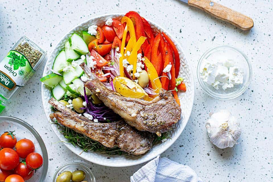 Juicy Greek Lemon Baked Pork Chops on top of a Greek salad.