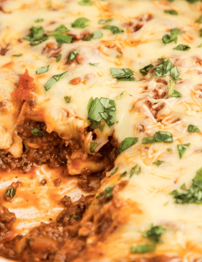 A close-up of a mouth-watering baked ravioli casserole in a white dish.