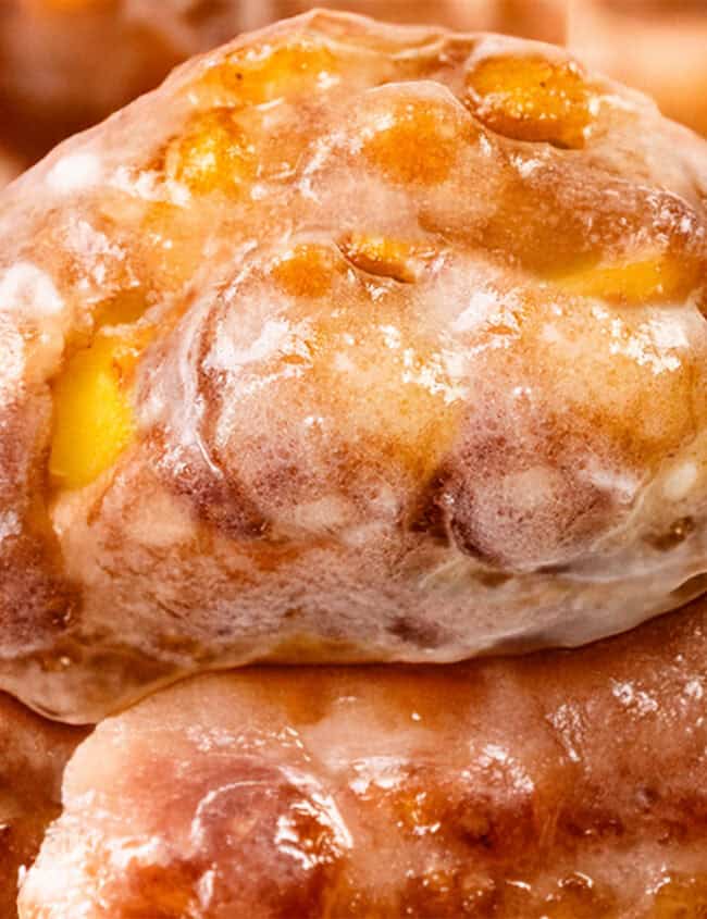 Close-up of glazed apple fritters from My Favorite Recipes, showcasing a glossy, caramelized surface with visible apple chunks and a golden-brown crust.