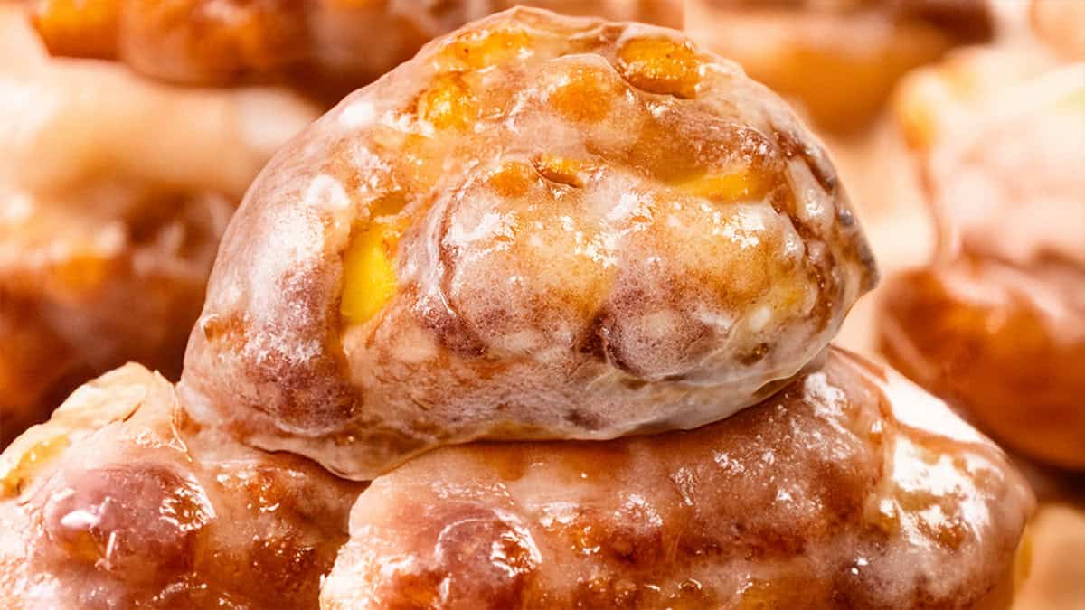 Close-up of glazed apple fritters from My Favorite Recipes, showcasing a glossy, caramelized surface with visible apple chunks and a golden-brown crust.