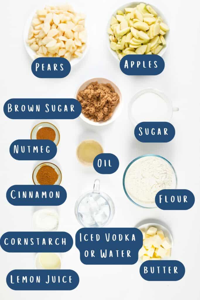 Top-down view of ingredients for a pear and apple pie recipe laid out on a white surface. Includes chopped pears, apples, brown sugar, sugar, nutmeg, cinnamon, oil, flour, cornstarch, iced vodka or water, lemon juice, and butter. Labels accompany each item.