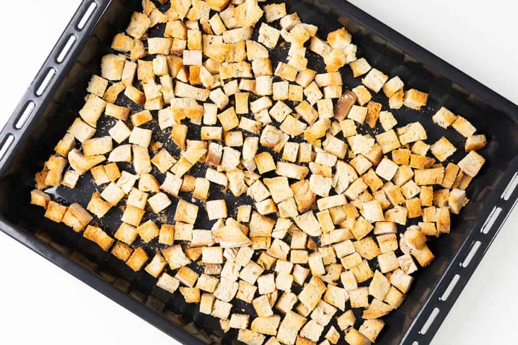 A baking tray filled with evenly spread, golden-brown croutons perfect for your make-ahead herb stuffing.