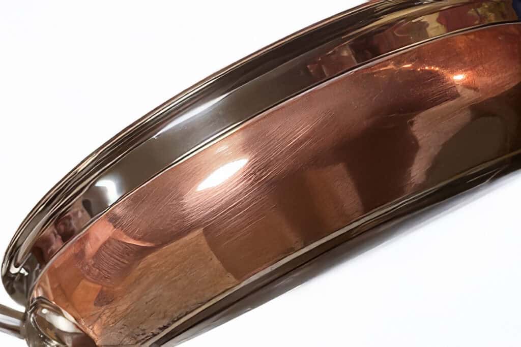 Close-up of a shiny Hestan CopperBond frying pan on its side, showcasing its polished, reflective surface. This exquisite piece of cookware is the best investment for any kitchen enthusiast.