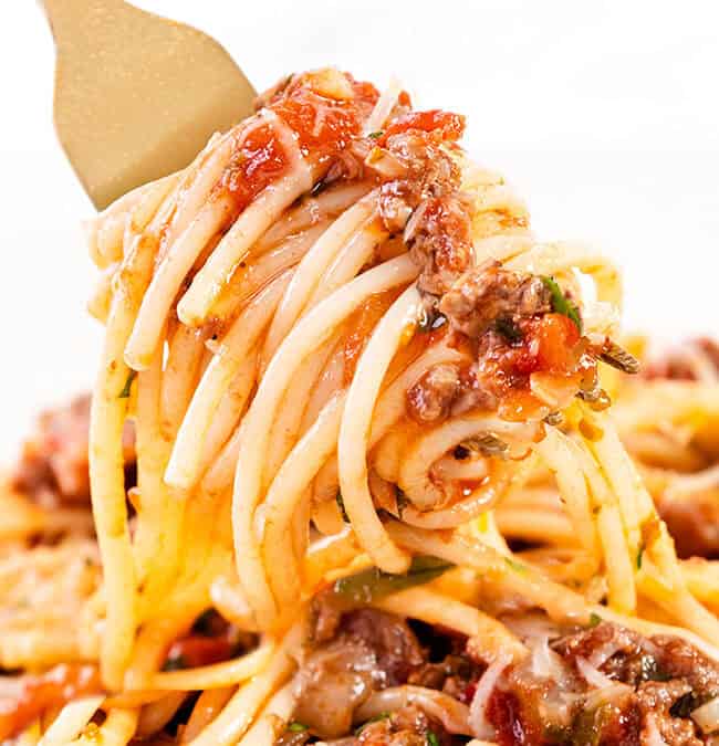 A fork twirls a serving of spaghetti with a rich meat sauce, featuring ground beef, tomatoes, and herbs. The dish is garnished with melted cheese, creating a comforting and savory meal.