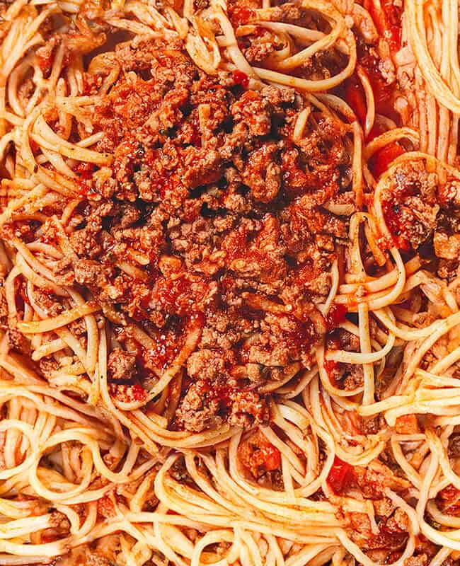 A close-up of spaghetti with a rich, savory meat sauce, featuring ground beef, tomatoes, and herbs. The pasta is evenly coated with the sauce, creating a hearty and appetizing classic dish.