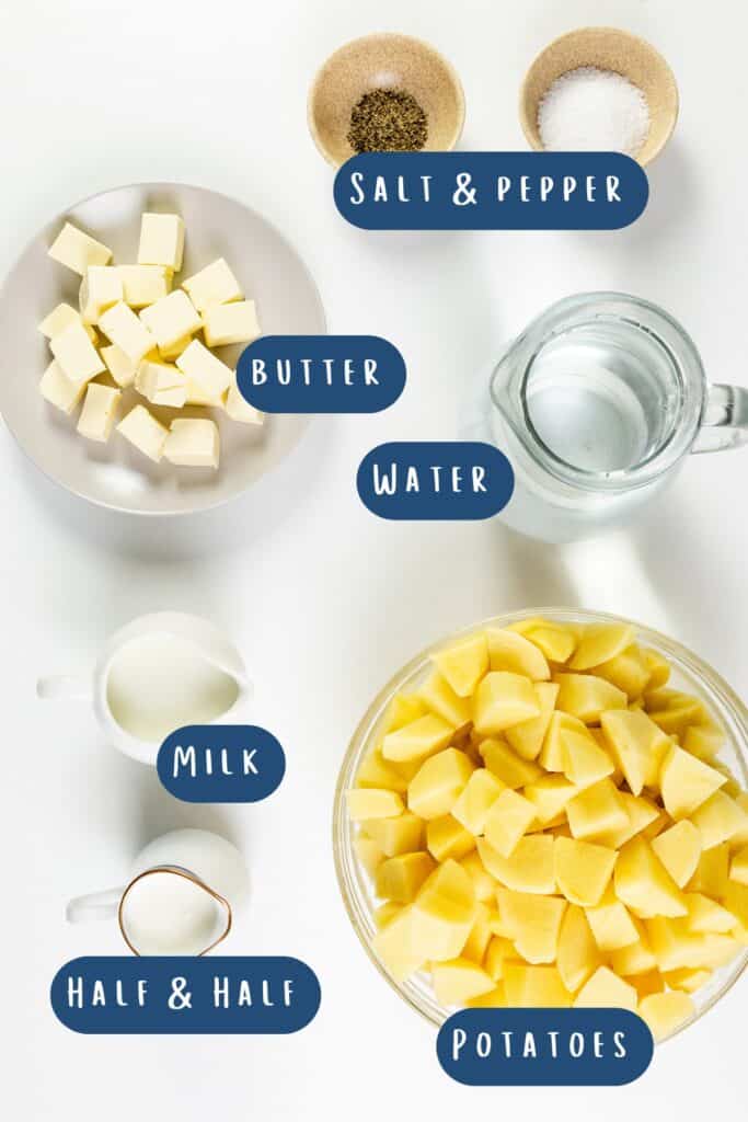 Ingredients for make-ahead mashed potatoes on a white surface: bowls of cubed butter, peeled and cubed potatoes, salt and pepper, a jug of water, and cups of milk and half & half cream. Labels neatly identify each ingredient.