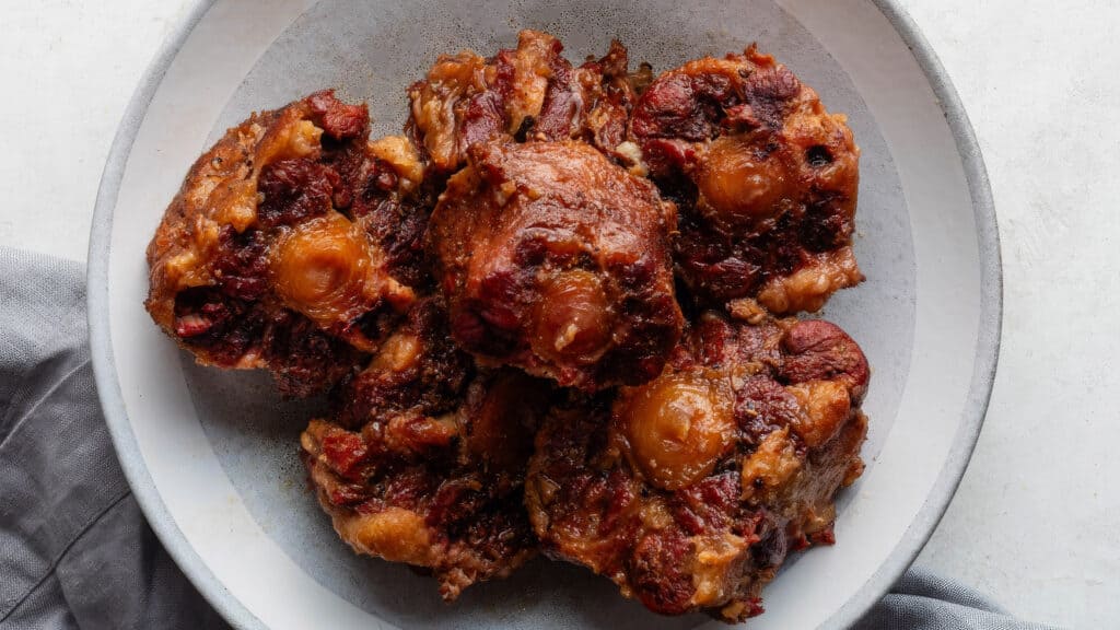 A white plate showcases a pile of sticky, caramelized, and golden-brown baked pastries filled with cherries and apricots, reminiscent of cherished Southern recipes. A gray cloth is partially visible beside the plate.