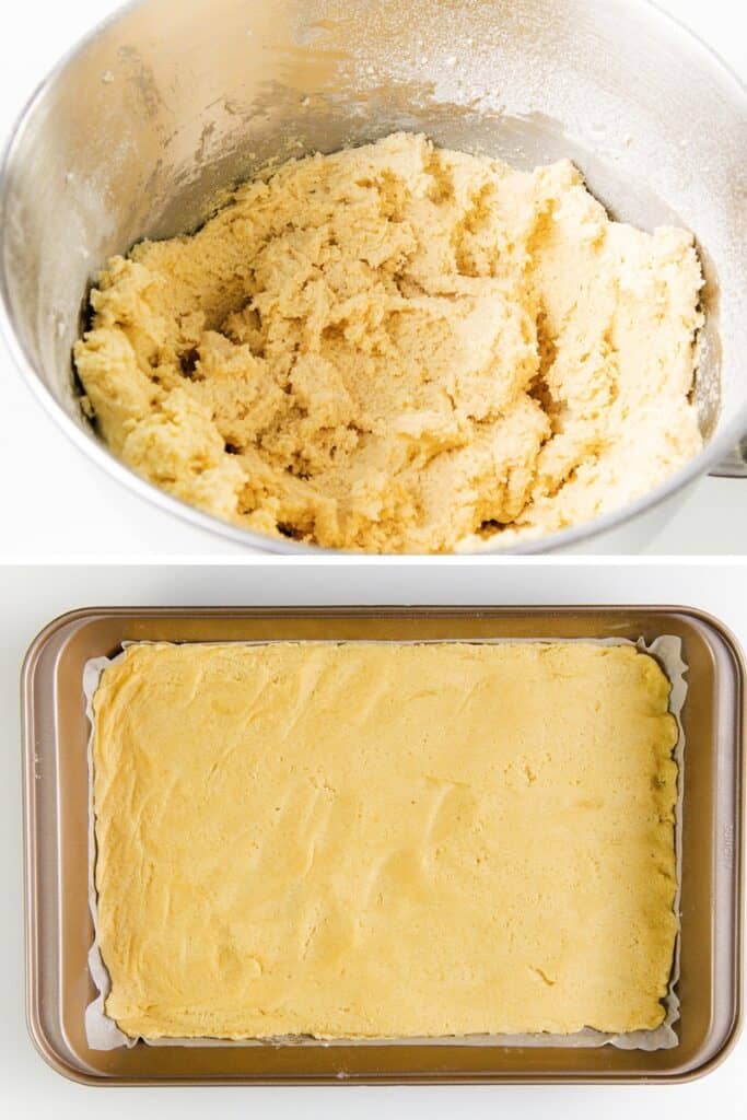 A mixing bowl filled with soft, yellow Snickerdoodle Bar dough sits above a parchment-lined baking tray. The cinnamon-sugar-infused dough is spread evenly across the bottom of the tray, ready for baking.