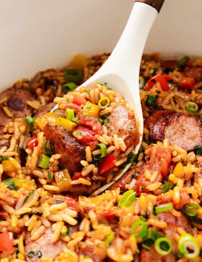 A delightful one-pot colorful rice dish featuring sliced sausage, red and yellow bell peppers, chopped green onions, and tomatoes mixed into the rice. This casserole appears fresh and flavorful.