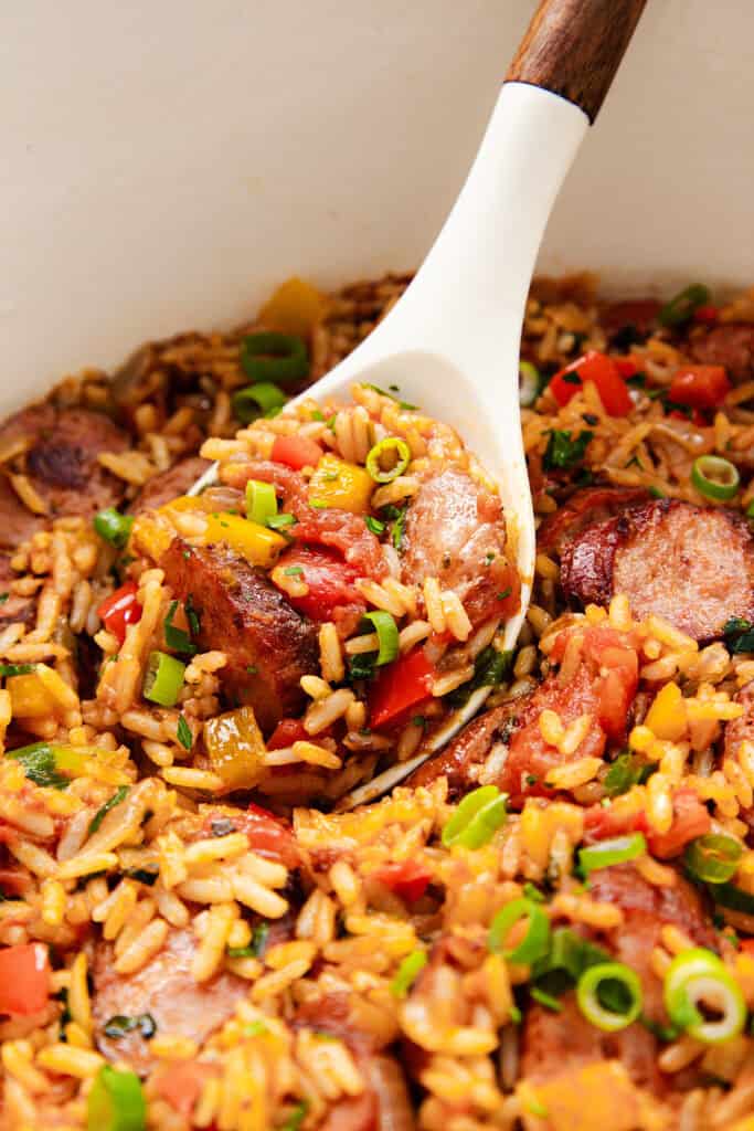 A delightful one-pot colorful rice dish featuring sliced sausage, red and yellow bell peppers, chopped green onions, and tomatoes mixed into the rice. This casserole appears fresh and flavorful.