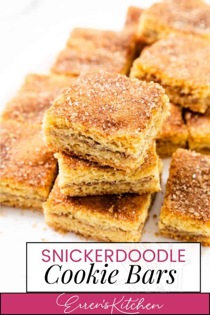 A stack of golden brown Snickerdoodle Bars sprinkled with cinnamon sugar is shown on a plate. The crumbly cookie bars exude a delicious aroma, and a label at the bottom reads "Snickerdoodle Cookie Bars - Erren's Kitchen." Perfect for those seeking classic snickerdoodle recipes.