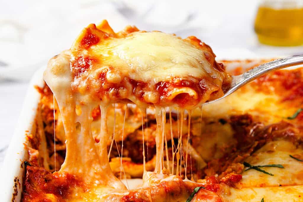 A close-up of a serving of Italian Sausage Ravioli Casserole being lifted from a dish.